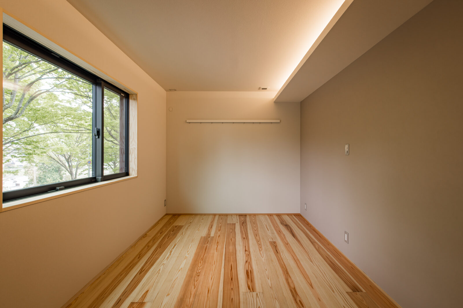 寝室には無垢フローリングを使用し、木のぬくもりと香りに包まれる空間に。 やわらかな間接照明を取り入れることで、明るすぎず落ち着いた雰囲気を演出しています。 窓の外には豊かな緑が広がり、心もほっと和らぎます。