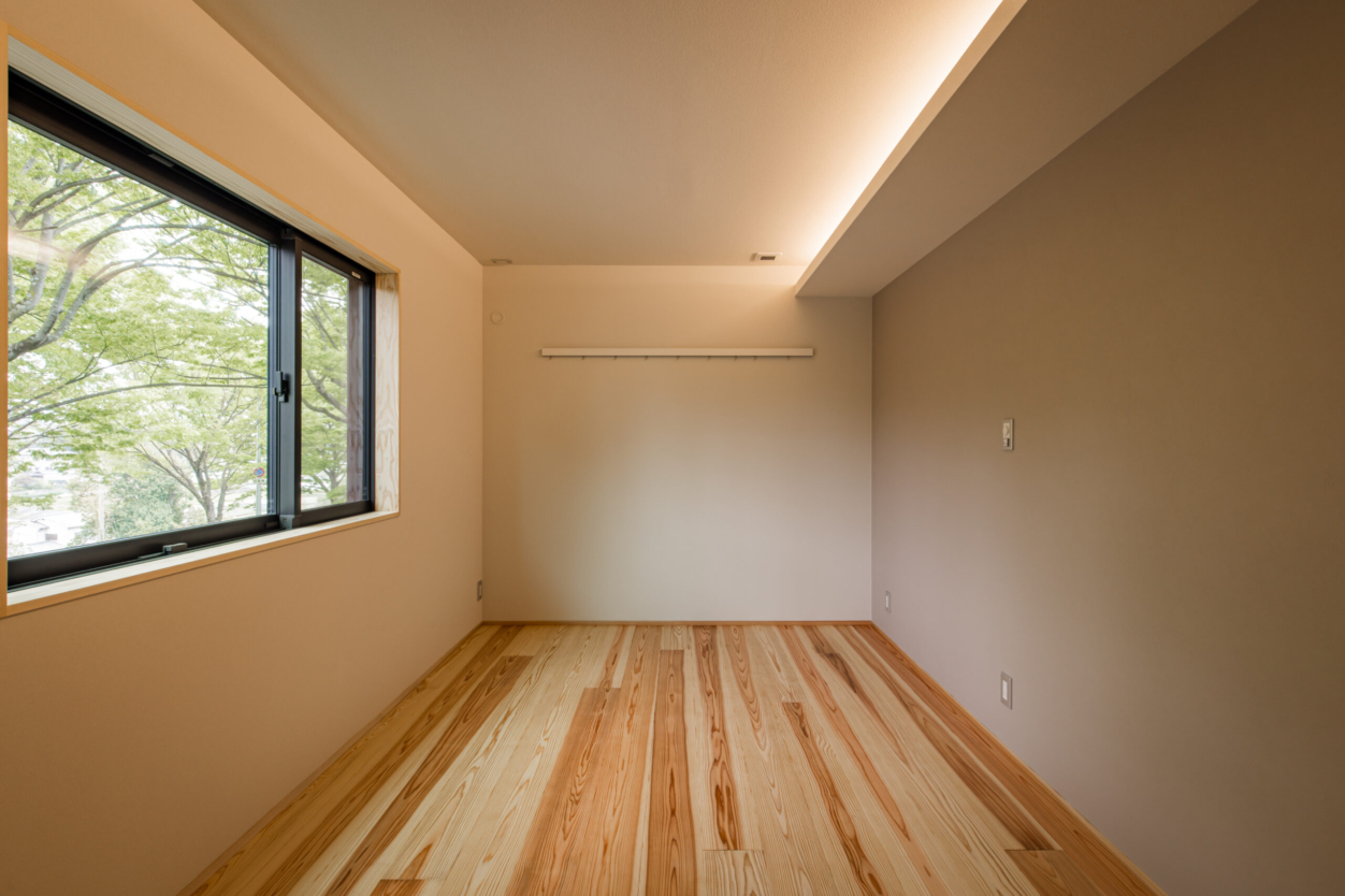 寝室には無垢フローリングを使用し、木のぬくもりと香りに包まれる空間に。 やわらかな間接照明を取り入れることで、明るすぎず落ち着いた雰囲気を演出しています。 窓の外には豊かな緑が広がり、心もほっと和らぎます。